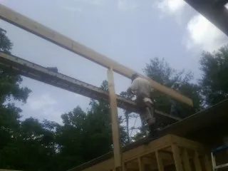 Carpenter setting a ridge beam over a new addition frame — Ice Dam Removal by Roofing Brothers in Mc Callsburg