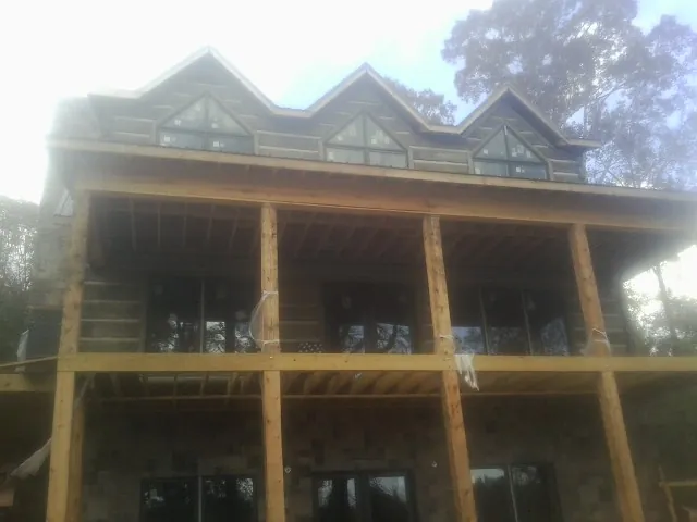 Dormers and porch framing on a large log home under construction — Roof Coating work by our crew in Mc Callsburg