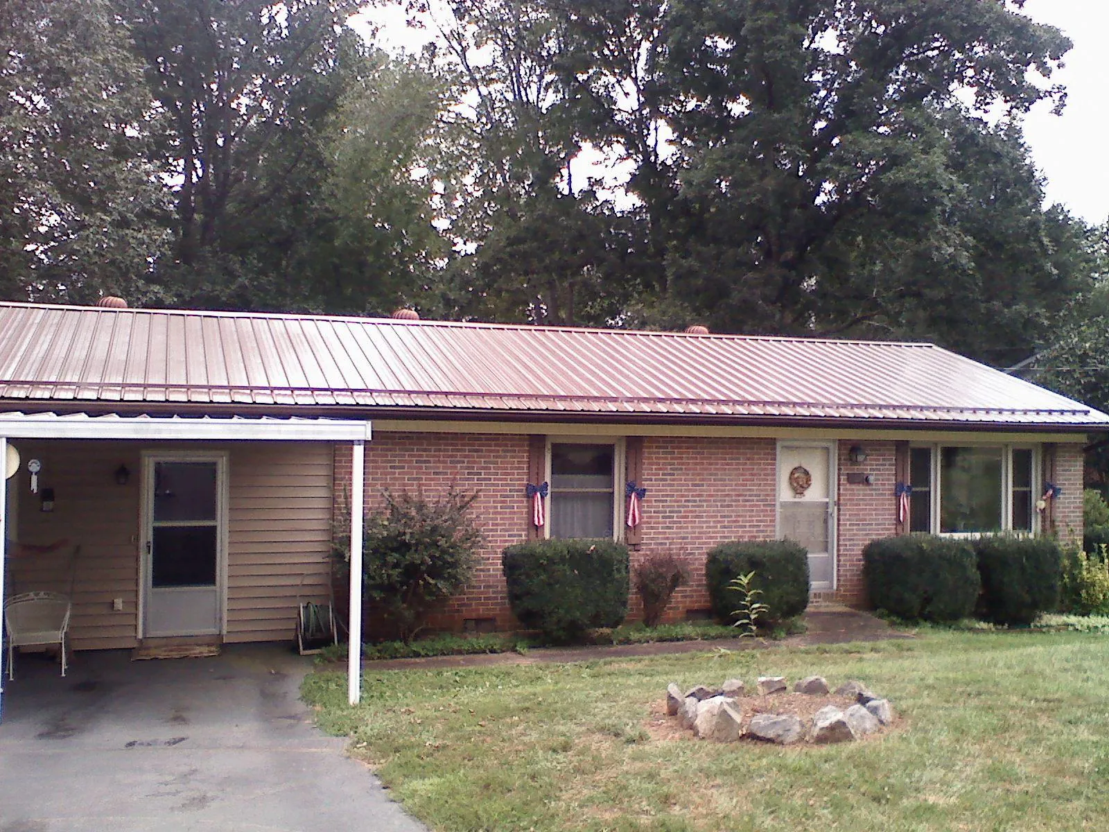 Bronze metal roof and carport on a brick ranch home — Roof Repair work by our crew in Mc Callsburg